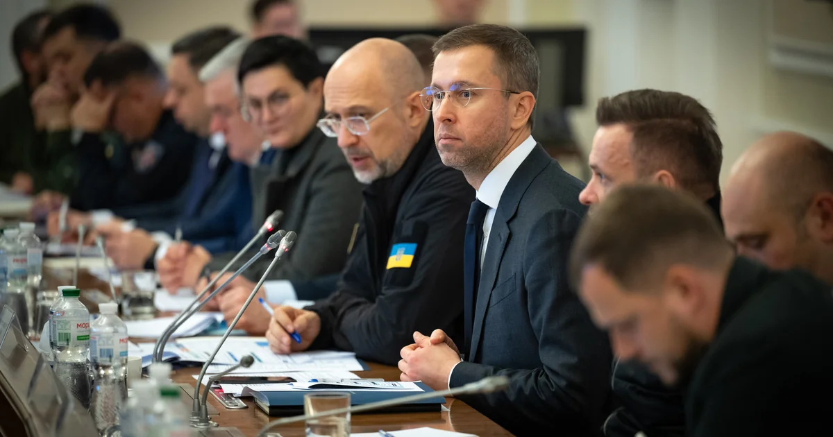 Учасники робочої наради за столом із документами та мікрофонами