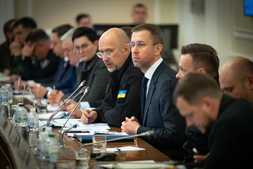 Учасники робочої наради за столом із документами та мікрофонами